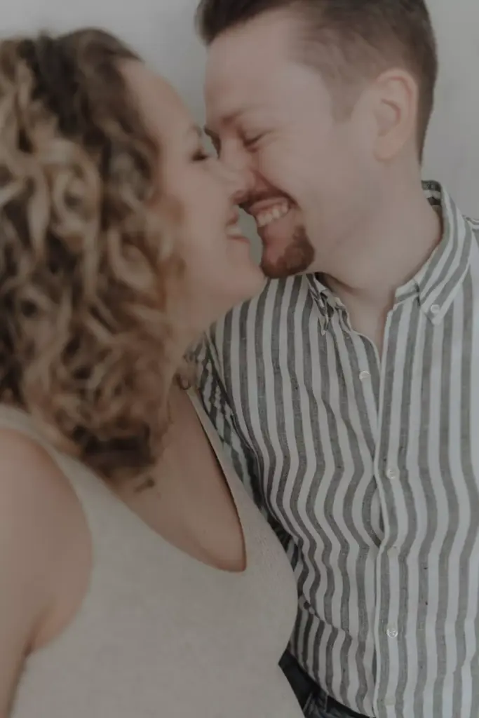 Lachendes Paar in inniger Umarmung bei einem Babybauch-Familienshooting